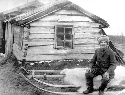 Житель села Каневка на санях рядом с избой