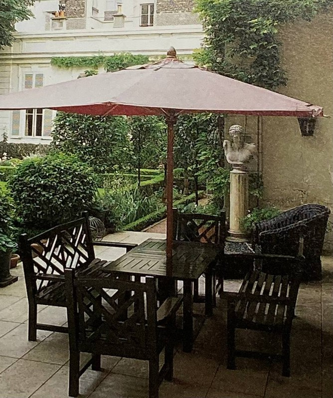 Вид на сад, открывающийся с террасы на соседнюю квартиру. Глициния начинает распускаться по стене.