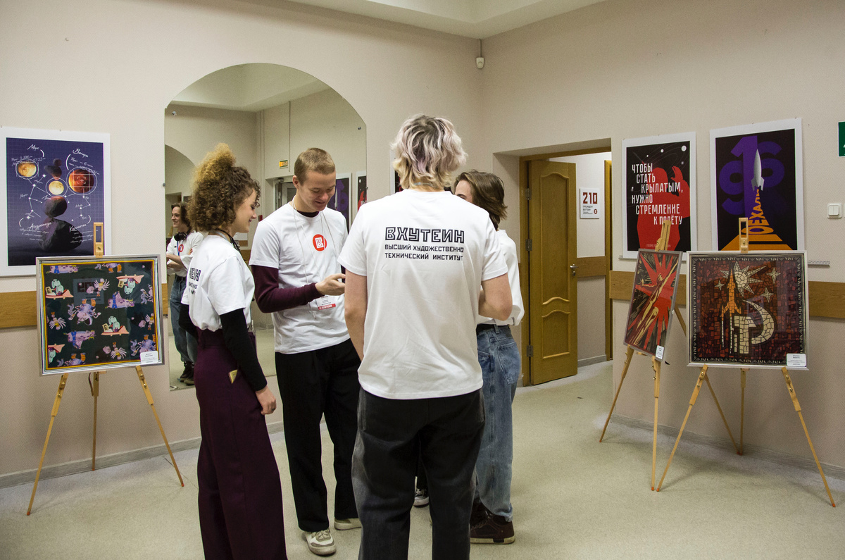 Волонтеры ожидают начало конференции в окружении организованных выставок творческих работ