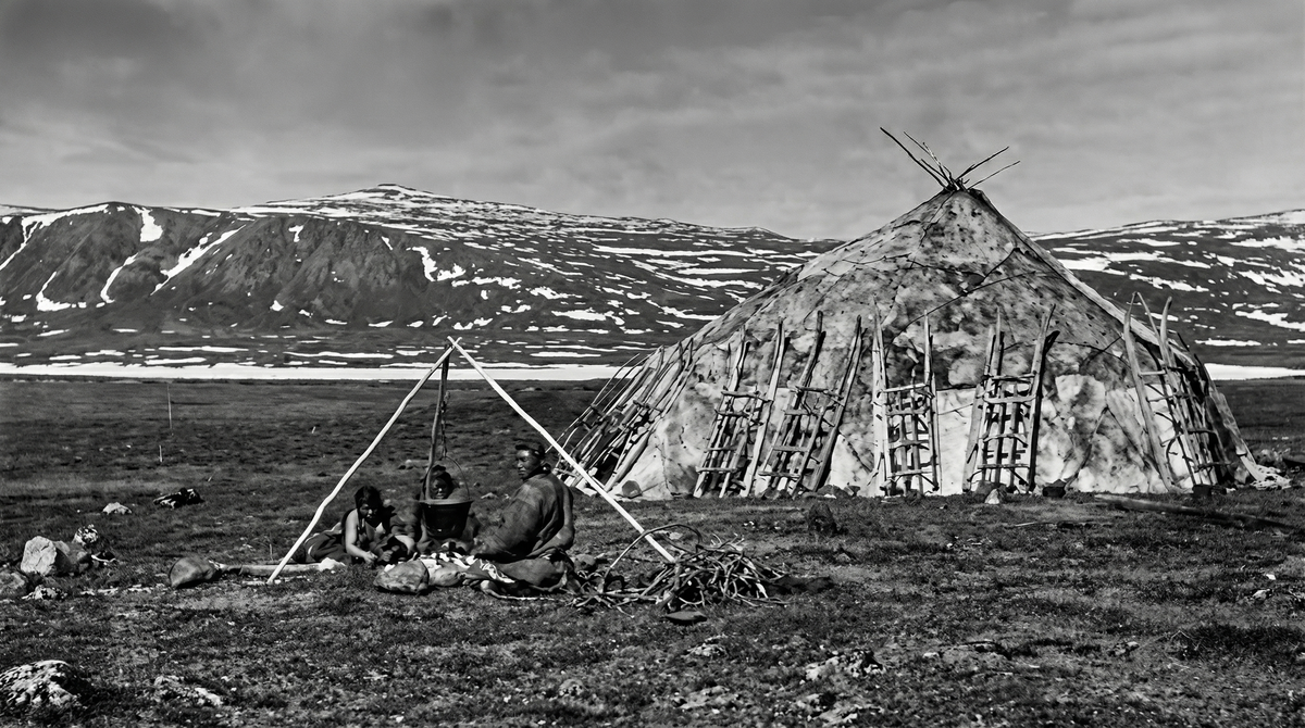 Костер на улице вблизи яранги; на треноге подвешен котел с варящимисяопаленными копытами