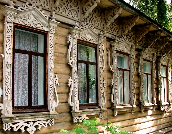Фасад старинного купеческого особняка или деревянного дома с богатой, замысловатой резьбой на наличниках и карнизах