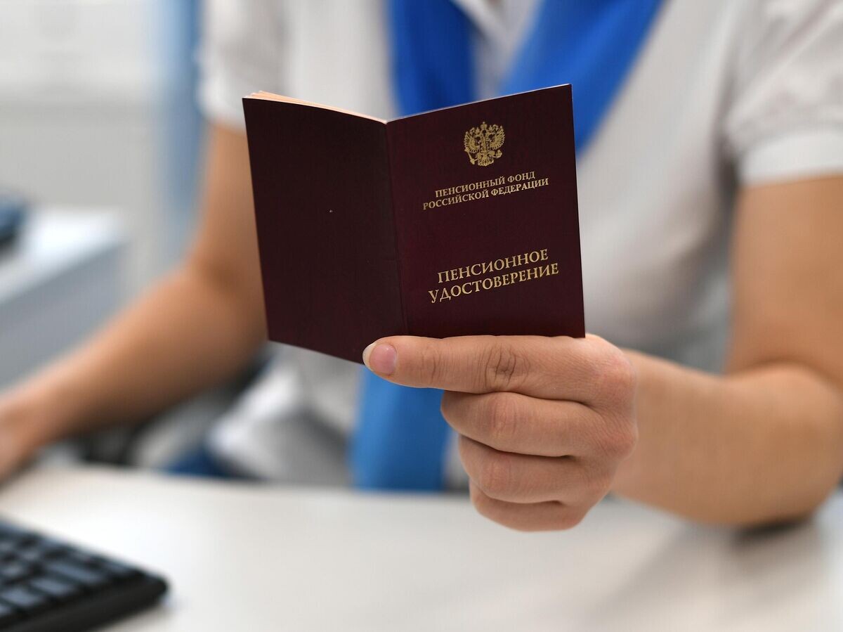    Сотрудник ПФР держит в руках пенсионное удостоверение© РИА Новости / Максим Блинов