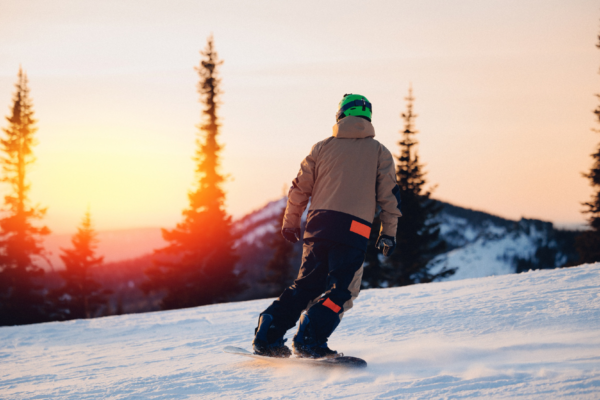 Сноубордист, занимающийся экстремальными зимними видами спорта на фоне заснеженного леса. Горнолыжный курорт Шерегеш, Сибирь. Источник фото: shutterstock.com