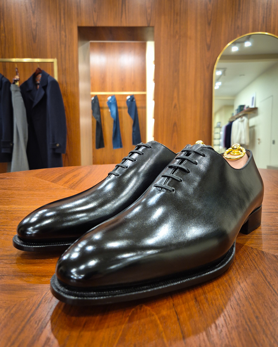 Черные цельнокройные оксфорды (Wholecut Oxford). Вершина обувного минимализма: модель сшита из единого куска кожи без лишних швов, что требует безупречного качества сырья. Самая строгая и элегантная пара в гардеробе, идеально подходящая для торжественных мероприятий и вечерних костюмов