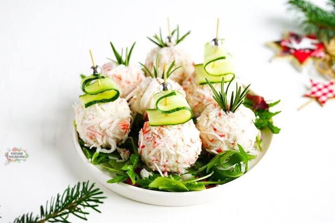 Это блюдо стало современной классикой благодаря своей простоте и нежному вкусу. Выглядит празднично и готовится за считанные минуты.
Ингредиенты:
Крабовые палочки: 200 г
Сыр твердый: 100 г
Яйца вареные: 2 шт.
Чеснок: 1 зубчик
Майонез: 2-3 ст. л.
Кокосовая стружка (по желанию для декора) или дополнительные крабовые палочки.
Приготовление:
Яйца и сыр натрите на мелкой терке.
Добавьте пропущенный через пресс чеснок и майонез, хорошо перемешайте до однородной массы.
Из получившейся массы сформируйте небольшие шарики.
Крабовые палочки измельчите в блендере или на мелкой терке.
Обваляйте каждый шарик в крабовой стружке или кокосовой стружке для более "снежного" эффекта. Охладите перед подачей.