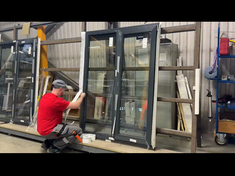 Монтажник устанавливает окно согласно ГОСТ 30971. Рабочий задувает монтажной пеной зазоры между окном и каркасом. После застывания пены оператор проклеивает специализированную ленту для замыкания пароизоляционного контура по периметру окна.