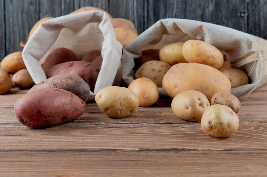    close up view of potatoes spilling out of sacks on wooden surface and background with copy space Круглова С.Б.