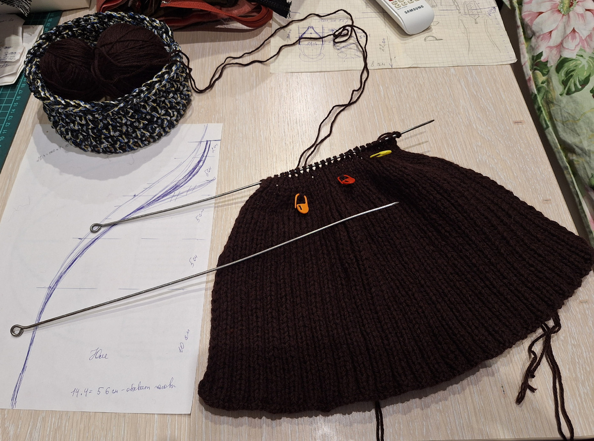 На этом этапе шапочка идёт на заужение. Рядом нарисовала форму шапки в натуральную величину. Вяжу и прикладываю иногда 