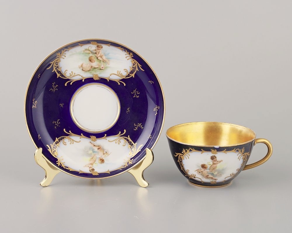 Чайная пара "Амуры-художники". Фарфор, крытье кобальтом, золотом, деколь, разделка золотом, d-14.3 см., h-5.3 cм., Россия, з-д Бр. Корниловых, кон.19-нач.20 века. Сохранность: скольчики, загрязнения, потертости, следы бытования. Продано за 11500 рублей