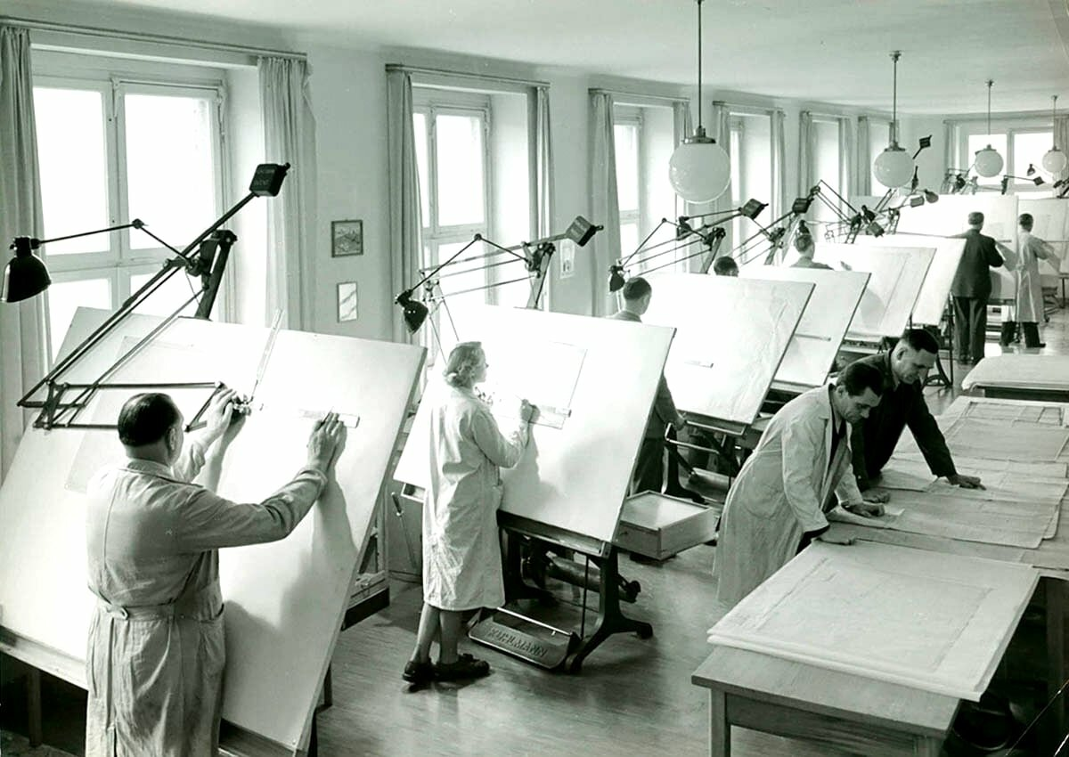 В этом зале — архитекторы. Они проектируют планировку, фасады, продумывают пропорции. В соседних комнатах — конструкторы и инженеры по сетям. Некоторые из них тоже работают по этому проекту. Конструктор рассчитывает, какие балки выдержат нагрузку. Инженер прокладывает водопровод и вентиляцию. У каждого — свой чертёж, но на стройке всё должно совпасть до миллиметра.