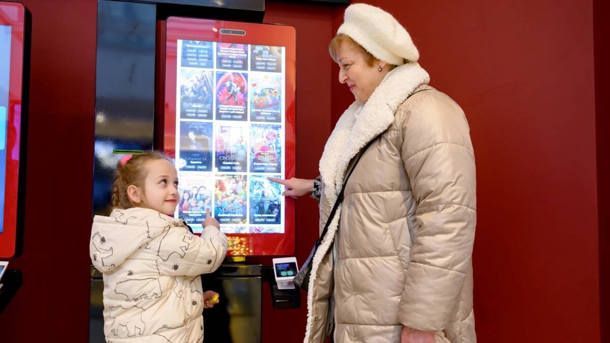    Москвичка Анна Миронова с внучкой Екатериной Красоткиной покупают билеты на показ фильма в кинотеатре «Рассвет» / Фото: Дмитрий Дубинский / Вечерняя Москва
