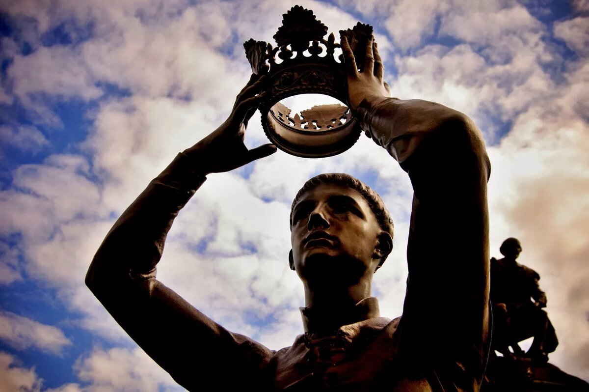 Памятник мужчины с короной в руках.