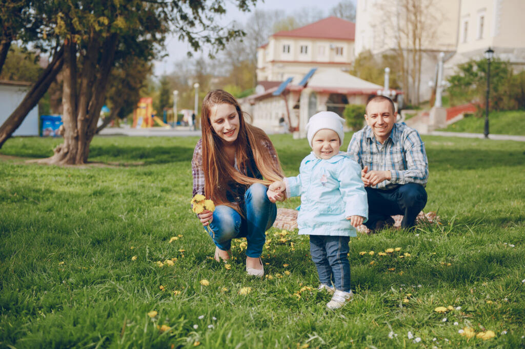    Beautiful mom with her husband and their little daughter in the spring park Журналист
