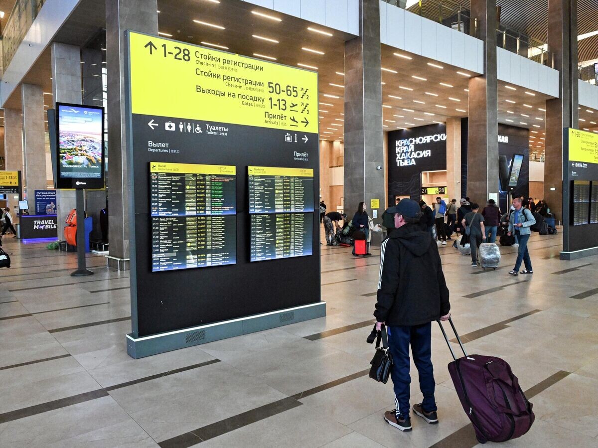    Пассажир у информационного табло в международном аэропорту Красноярск им. Дмитрия Хворостовского | © РИА Новости / Илья Наймушин