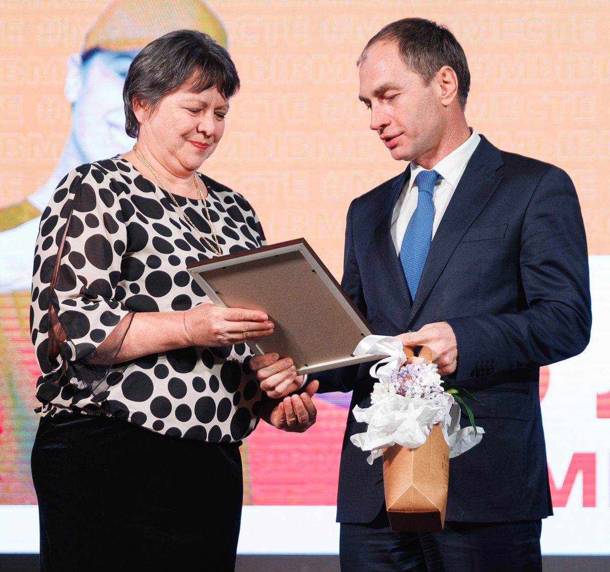 Евгений Поляков вручает награду добровольцу инициативной группы «Сердце фронта» Елене Орловой. Фото Мурата ХУТОВА.