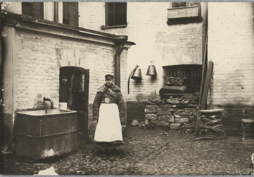 Дворник у бака с водой во дворе городского дома. Фото с сайта goskatalog.ru