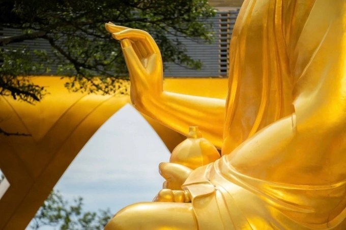 Правая рука Будды Гона Хама делает обучающий жест, левая рука держит инжир.