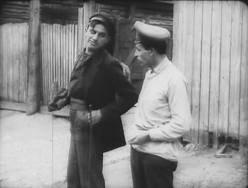 Хулиган (В. В. Маяковский в роли хулигана) отбирает у прохожего кулёк с монетами. Кадр из фильма «Барышня и хулиган», 1918 г.