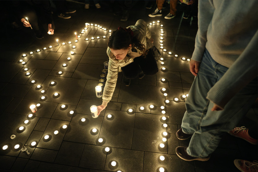 Люди зажигают свечи в память о жертвах трагедии
 Фото: Abir Sultan / EPA / TASS