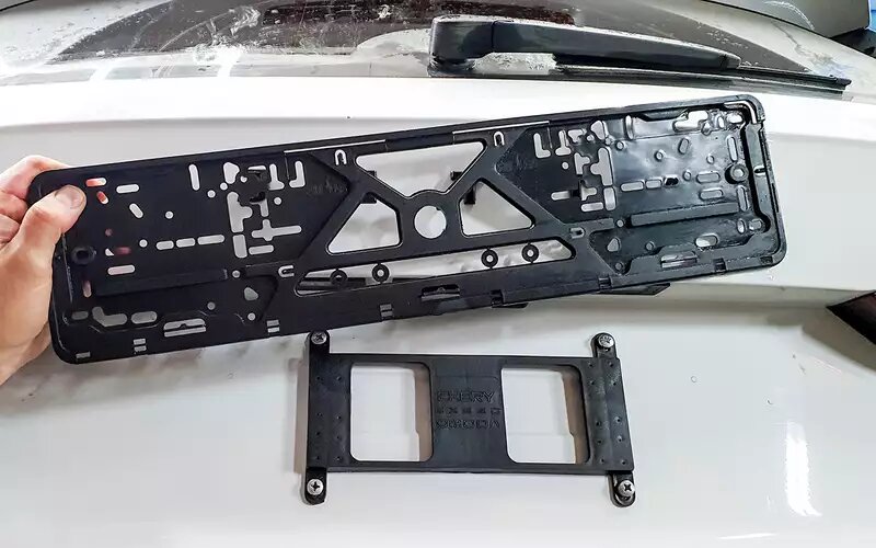    Небольшая пластмассовая переходная плита, к которой крепится короткими саморезами обычная рамка под наш номер. За комплект из переходника и рамки возьмут примерно 1200 рублей.