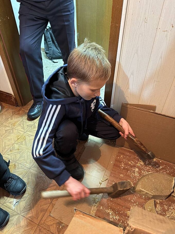 Мальчик измельчает воск топором и киянкой