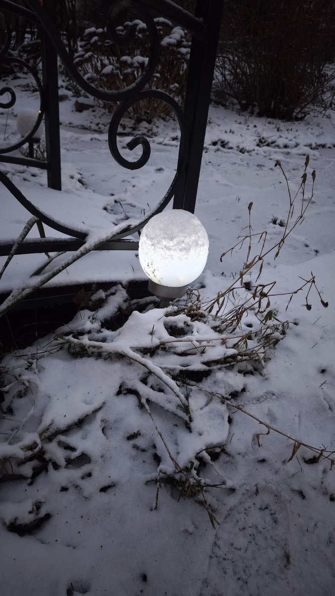 Очень загадочно светит фонарик, забытый на улице. С одной стороны, его надо бы в дом, поберечь аккумулятор, а с другой стороны, мне нравится, как он светит под снегом.