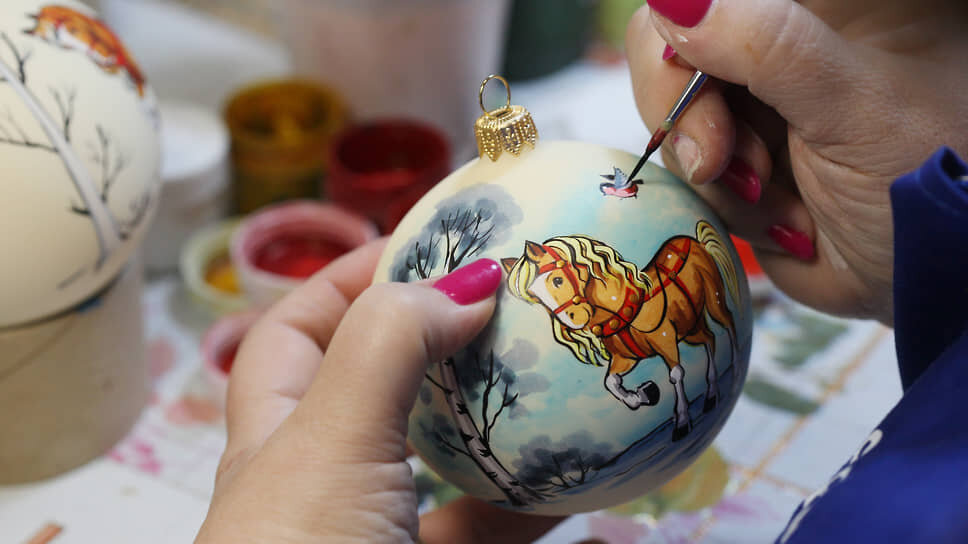 Художница расписывает елочный шар с изображением коня, символа 2026 года.📷Фото: Роман Яровицын / Коммерсантъ