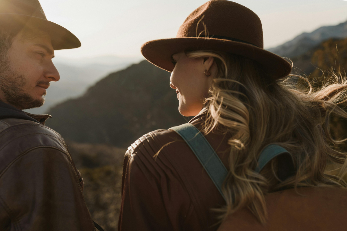 Друзья в путешествии смотрят друг на друга на фоне гор, совместная поездка и атмосфера приключения в дороге