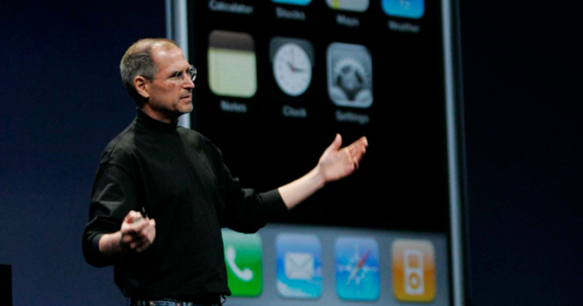 9 января 2007 года **Стив Джобс** вышел на сцену Macworld Expo в Сан-Франциско и сделал то, что позже назовут переломным моментом в истории технологий. Он объявил о «трёх революционных продуктах» — iPod с широким экраном, мобильном телефоне и интернет-устройстве — и спустя паузу уточнил: это один девайс. iPhone. Без стилуса — пальцы оказались умнее. Multi-Touch (мультитач-управление) стал новым языком взаимодействия с экраном. Устройство работало на базе настольной macOS, обеспечивая полноценный интернет через Safari. Экран 3,5 дюйма, камера 2 Мп и память 4 или 8 ГБ — характеристики, которые сегодня выглядят скромно, но тогда обозначили начало новой эпохи.