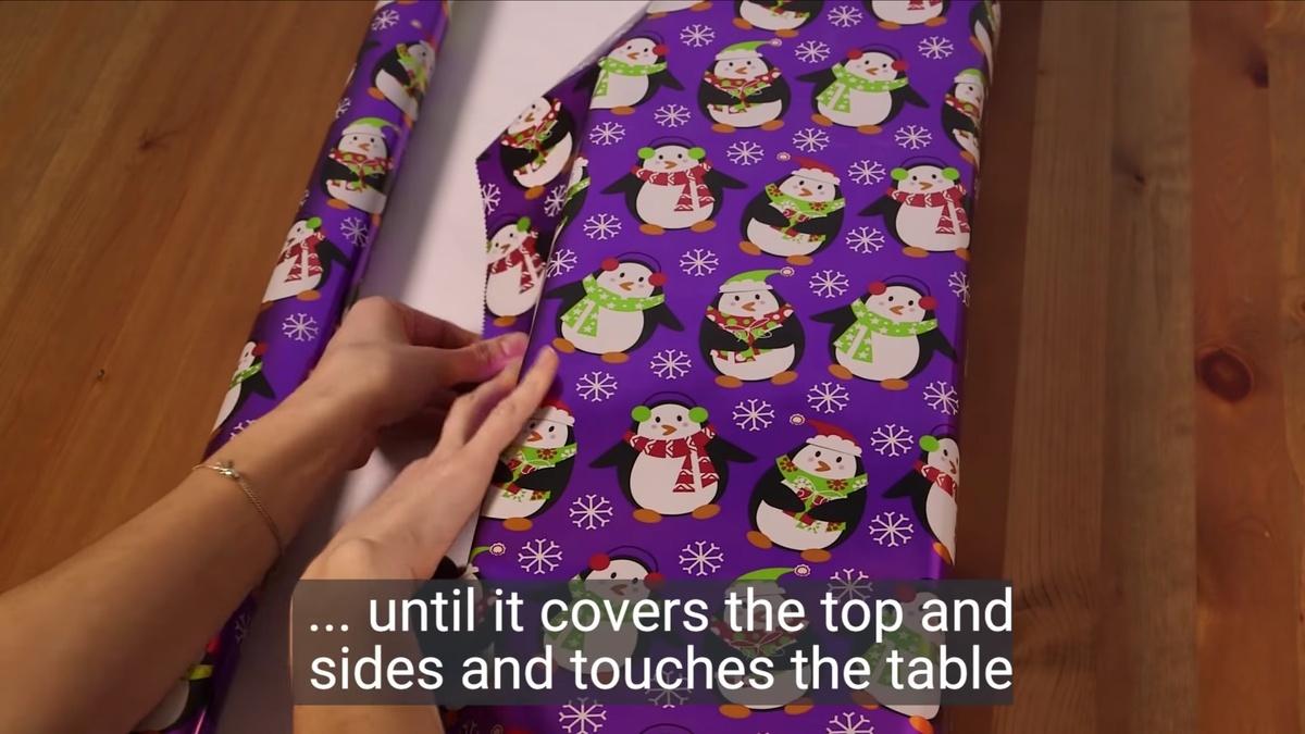 YouTube / Business Insider📷Шаг 2. Отмеряем бумагу по сторонам, загибаем так, чтобы верхняя часть была внахлест и заканчивалась на сгибе коробки. Оставшуюся часть отрезаем.