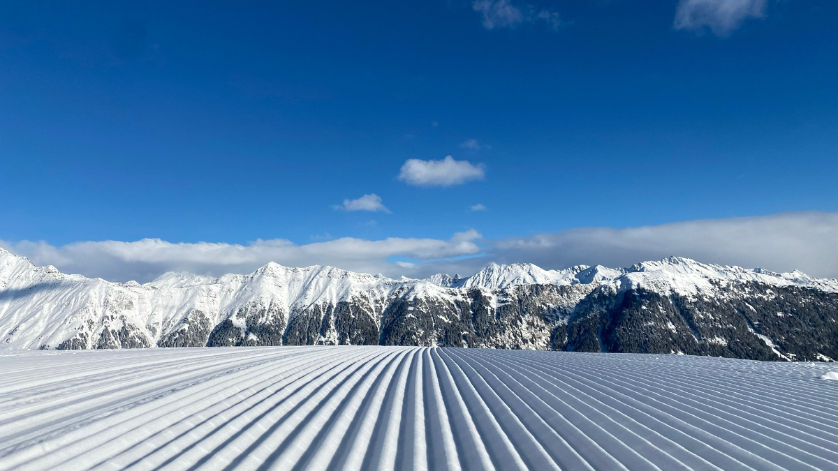 Снимок лыжного курорта Роза Хутор со слоями снега на фоне голубого неба и гор. Источник: Shutterstock