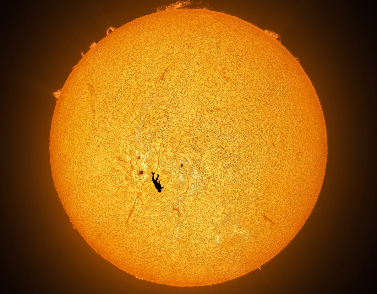    «Прогулка по Солнцу». Парашютист совершает прыжок, и его силуэт идеально очерчен на фоне солнечной поверхности. На заднем плане видны темные пятна — они возникают в местах, где мощные магнитные поля блокируют часть тепла, обычно поднимающегося на поверхность. Астрофотографу Эндрю Маккарти и скайдайверу Гэбриелу Брауну потребовались месяцы планирования и ювелирный расчет времени, чтобы сделать этот впечатляющий снимок с помощью специального солнечного телескопа.