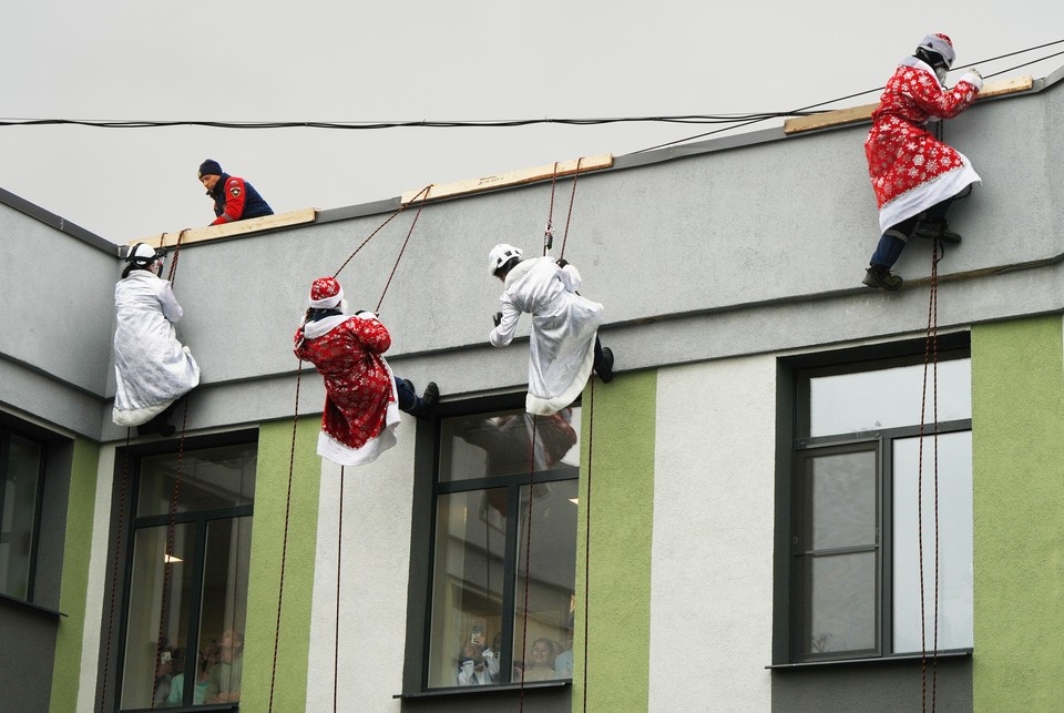    Студенты-спасатели в образах Деда Мороза и Снегурочки спускаются к детям с крыши медучреждения Александр ИВАНОВ