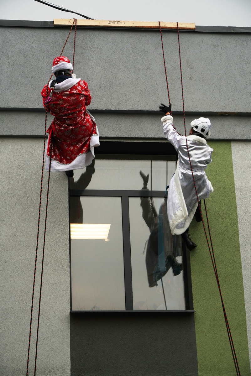    Студенты-спасатели в образах Деда Мороза и Снегурочки спускаются к детям с крыши медучреждения Александр ИВАНОВ
