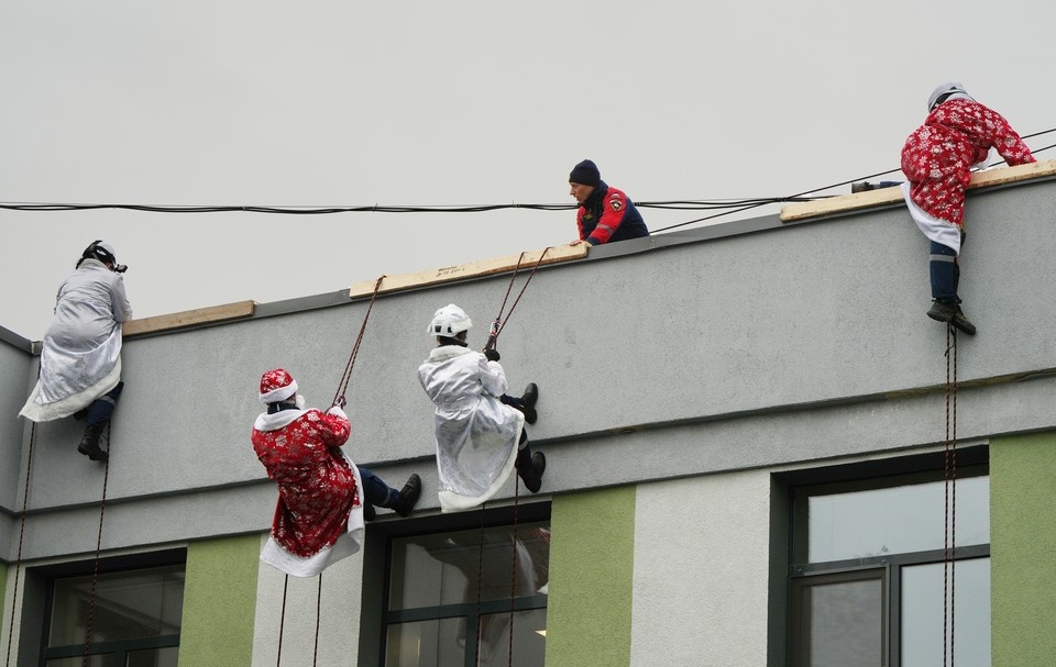    Студенты-спасатели в образах Деда Мороза и Снегурочки спускаются к детям с крыши медучреждения Александр ИВАНОВ