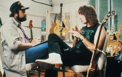 Кадр из фильма. Роб Райнер в роли режиссера-документалиста Марти Ди Берджи берет интервью у Кристофера Геста, который играет музыканта вымышленной группы Spinal Tap Нигеля Тафнела.