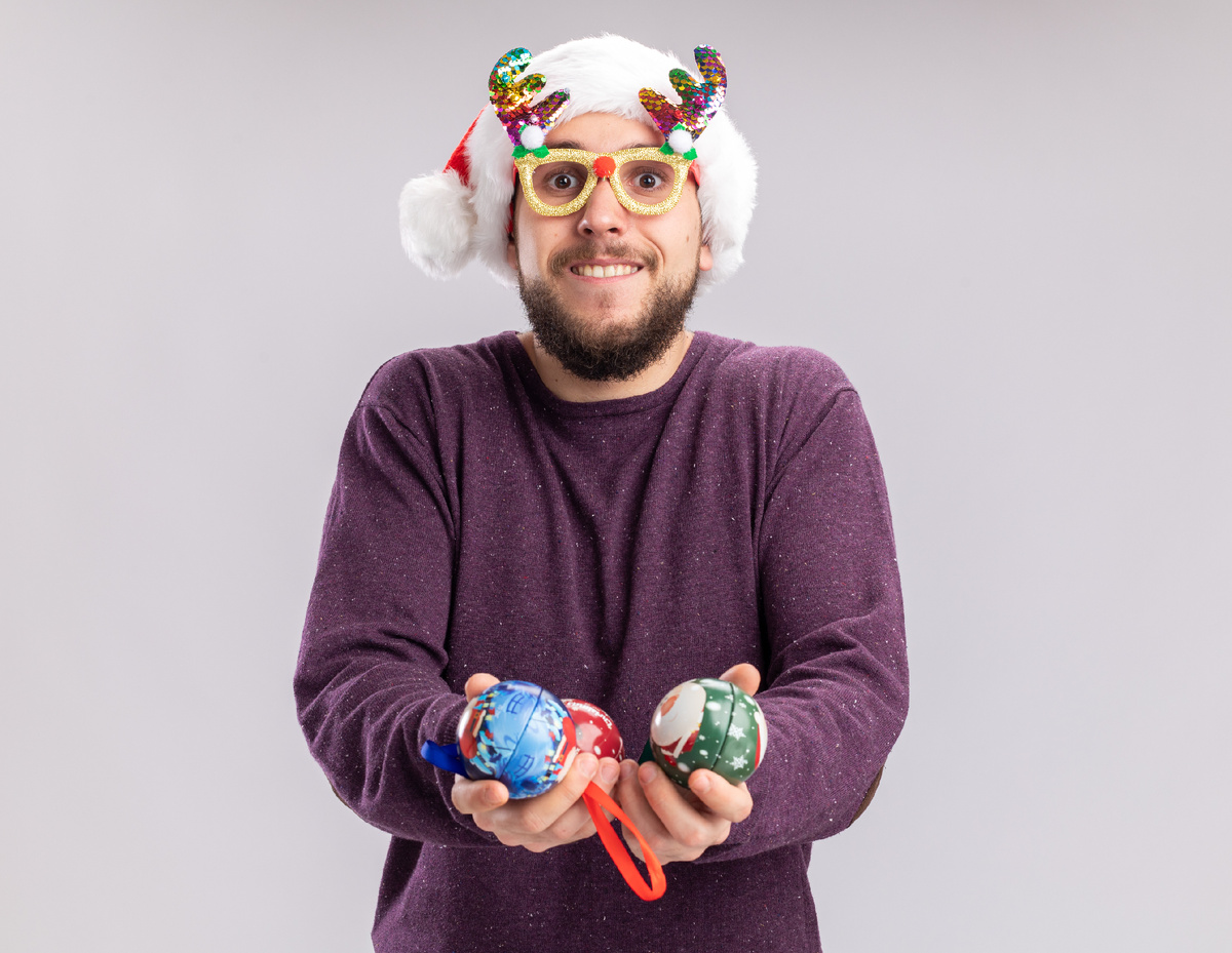 <a href="https://ru.freepik.com/free-photo/young-man-purple-sweater-santa-hat-wearing-funny-glasses-holding-christmas-balls-looking-camera-confused-smiling-standing-white-background_11700149.htm">Изображение от stockking на Freepik</a>