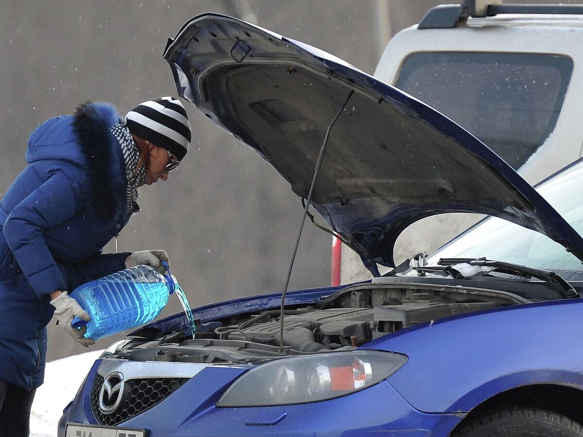    Женщина заливает незамерзающую жидкость для омывания стекол автомобиля на МКАДе в Москве© РИА Новости . Рамиль Ситдиков