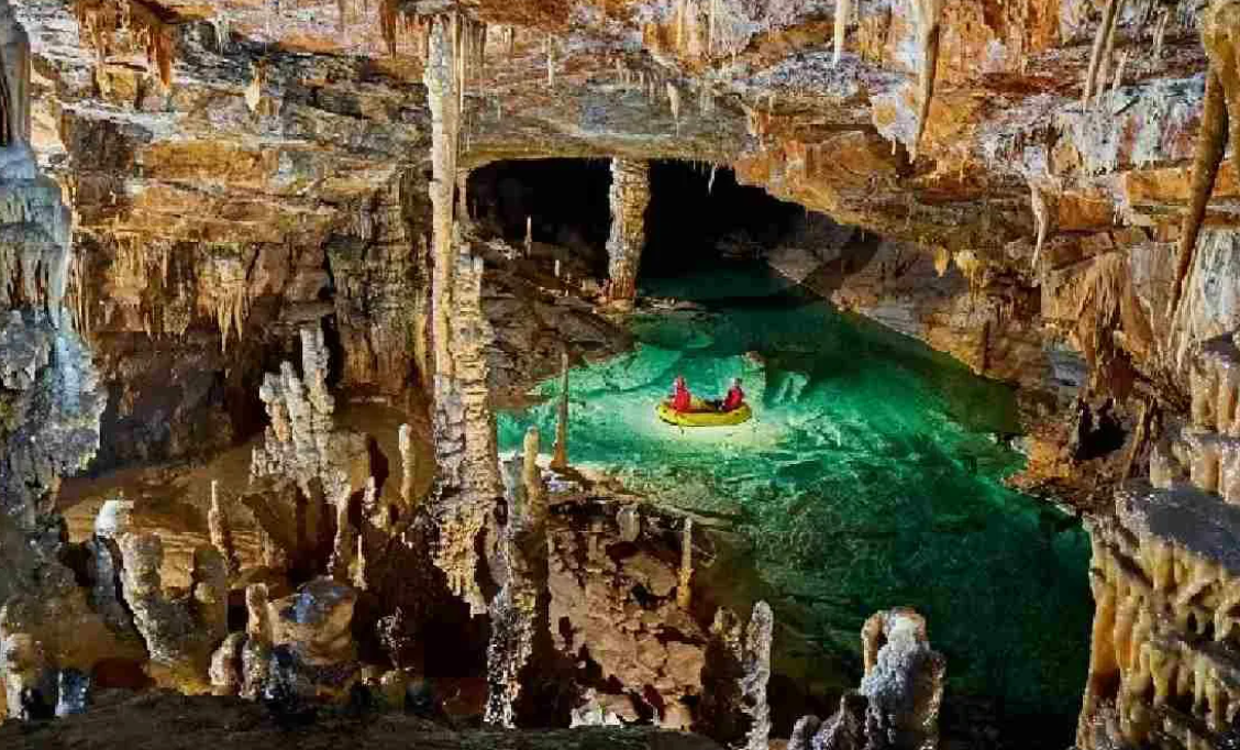 Лодка плывет  по подземной реке в пещере Алтынбешик.