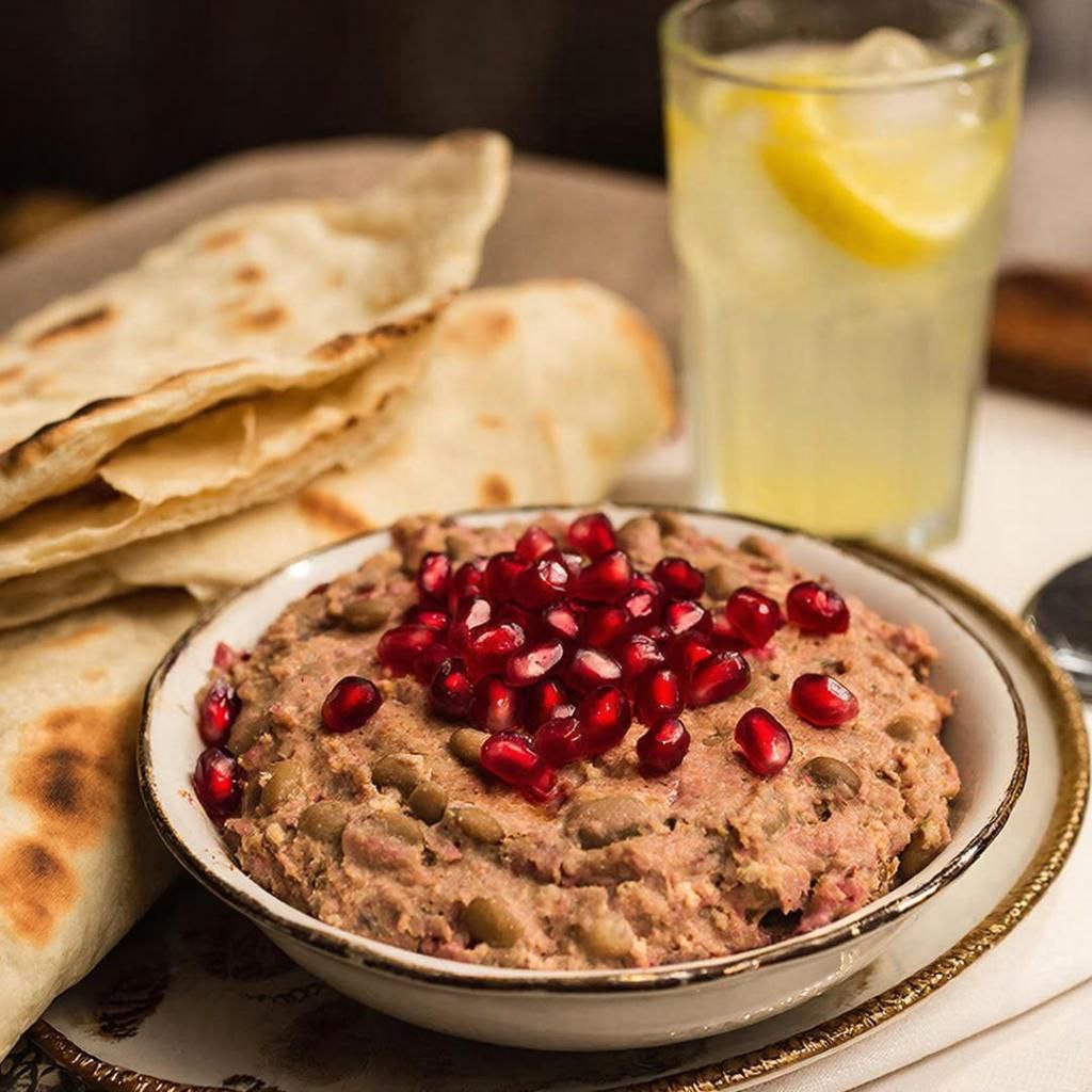 нежный паштет из фасоли , украшенный зернами граната, рядом стакан с лимонадом и хлеб, испеченный в  каменной печи
