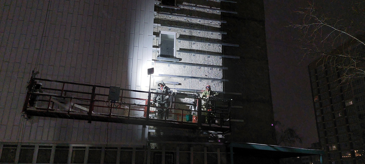 По темноте с утра рабочие утепляли фасад общежития.