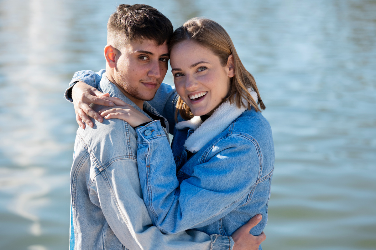 Молодая пара обнимается у воды, показывая близость, доверие и гармонию в отношениях