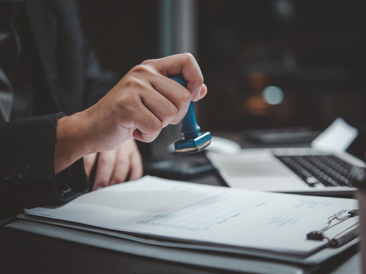    Человек ставит печать на финансовые документы | © iStock.com / hirun