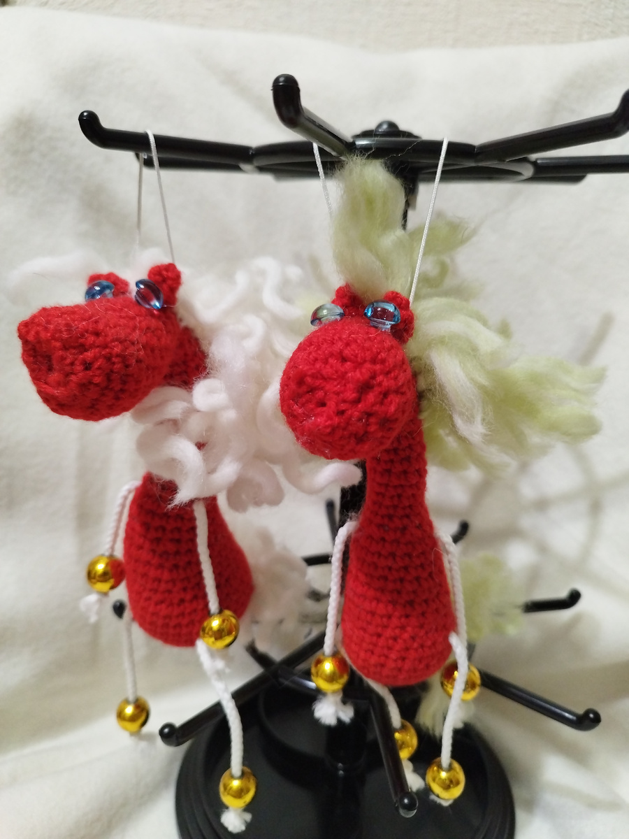 Клубок алой шерсти, умело обёрнутый вокруг ловких пальцев, постепенно обретает форму. С каждым стежком, с каждым точно рассчитанным движением крючка, из бесформенной массы вырисовываются очертания. Очертания лошади. Не просто лошади, а миниатюрного символа, воплощающего в себе уют, тепло и новогоднее волшебство.

Её шерстка, насыщенного, почти рубинового оттенка, мерцает в свете гирлянд. Грива и хвостик, связанные из более тонкой пряжи, свободно развеваются, придавая игрушке динамику и живость. Маленькие черные глазки-бусинки смотрят с детской наивностью и добротой.

Эта вязаная лошадка – не просто украшение. Это маленький талисман. Она может украсить новогоднюю елку, добавив ей нотку ручной работы и индивидуальности. Может стать забавным акцентом на зеркале заднего вида автомобиля, напоминая о приближающихся праздниках и радостных моментах. А может поселиться на любимой сумке, став милым и оригинальным аксессуаром, привлекающим внимание и вызывающим улыбку.

Каждый стежок в этой лошадке – это частичка души, вложенная мастером. Она согреет в холодные зимние вечера, подарит хорошее настроение и станет прекрасным подарком для близкого человека. Ведь вещи, сделанные своими руками, всегда несут в себе особую ценность и теплоту. Они – как кусочек солнца, заключенный в нити шерсти, способный растопить лед даже в самом холодном сердце.