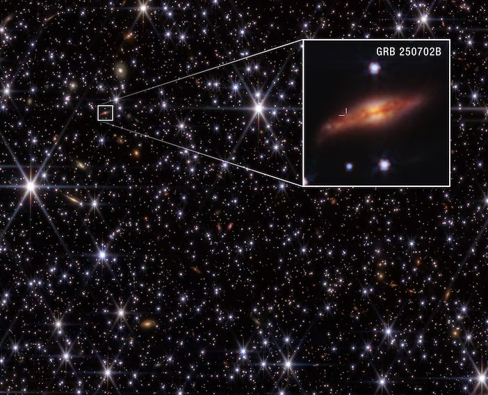 Телескоп «Джеймс Уэбб» предоставил астрономам наиболее четкое изображение галактики, в которой находится GRB 250702B. На увеличенном фрагменте положение вспышки у верхнего края темной пылевой полосы галактики исключает возможность того, что вспышка была связана со сверхмассивной черной дырой в ядре галактики.