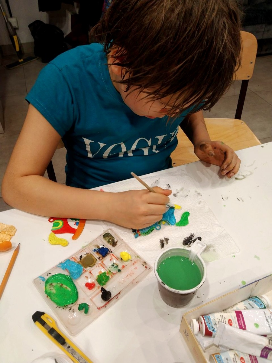 Сеня заканчивает расписывать синюю лошадку. 