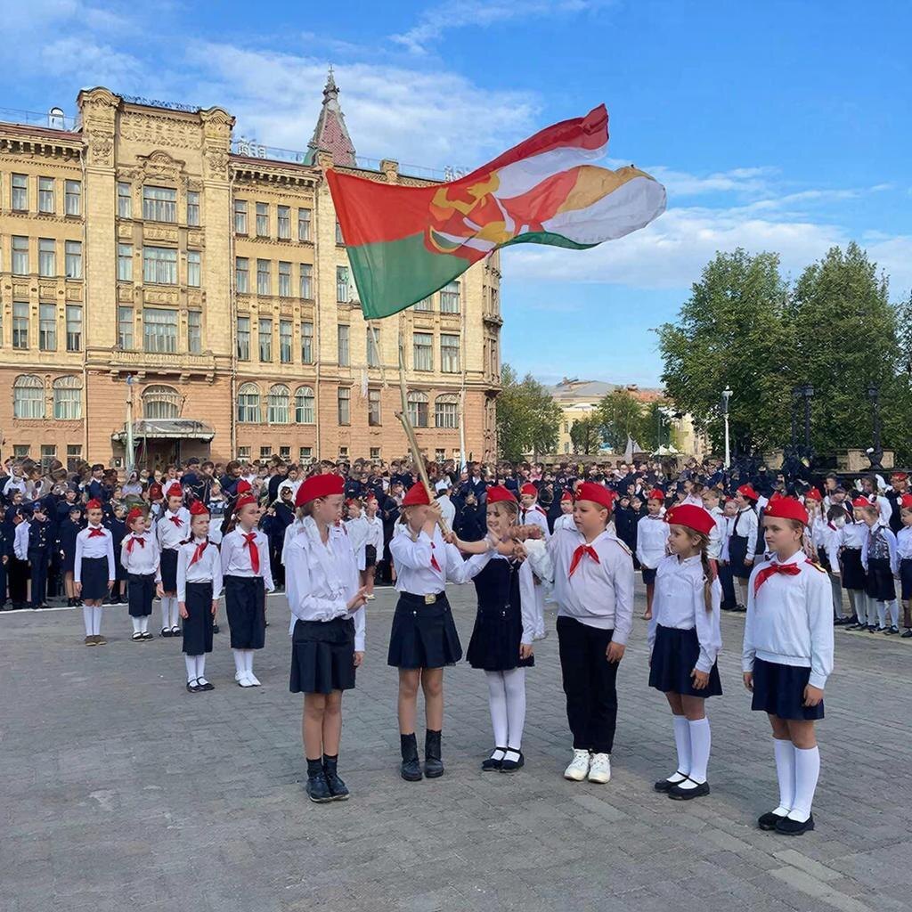 Сцена церемонии принятия в пионеры, где дети дают клятву и поднимают флаг.
