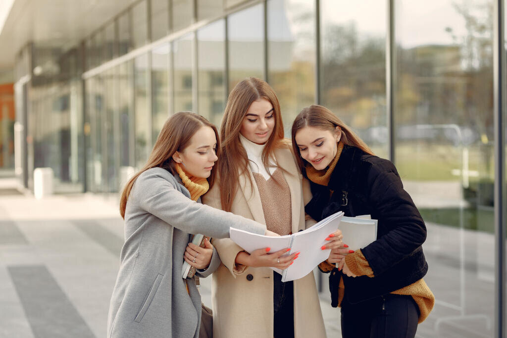    Students in a park. Girls on a campus. Friends with a documents. Журналист