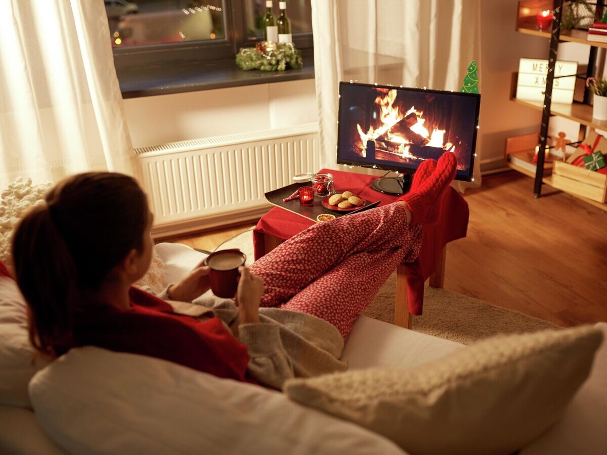    Девушка сидит перед телевизором на Новый Год | © Depositphotos.com / Syda_Productions