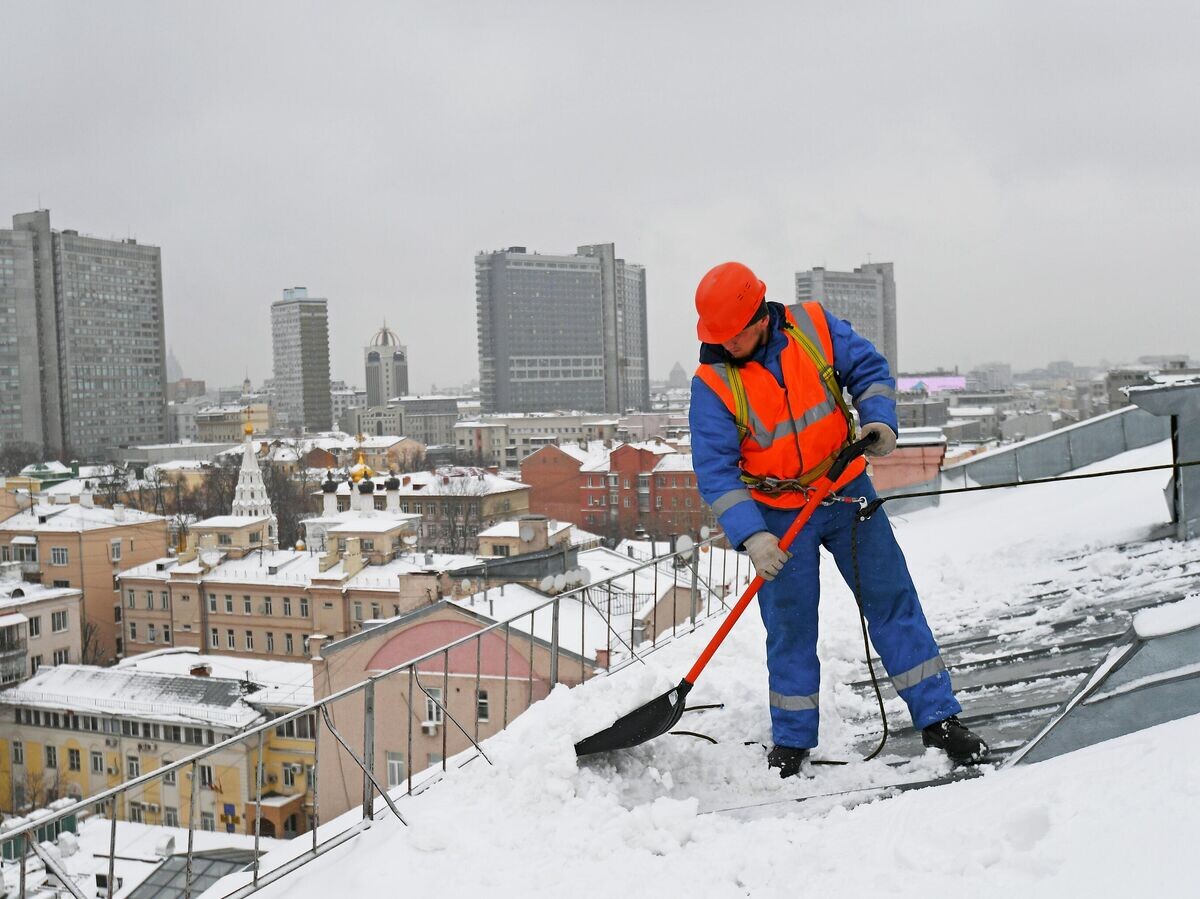    Сотрудник коммунальных служб отчищает крышу одного из домов в Москве | © РИА Новости / Владимир Песня